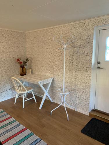 a white table and chair in a room with a wall at Gårdshus 1 in Örby