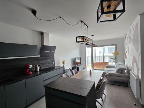 une cuisine et un salon avec une table et des chaises dans l'établissement Appartement 2 chambres neuf bord de plage, à Royan
