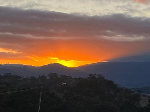 a sunset in the mountains with the sun setting at Chalé Estância da Pinha seu Refúgio na Montanha in Santo Antônio do Pinhal