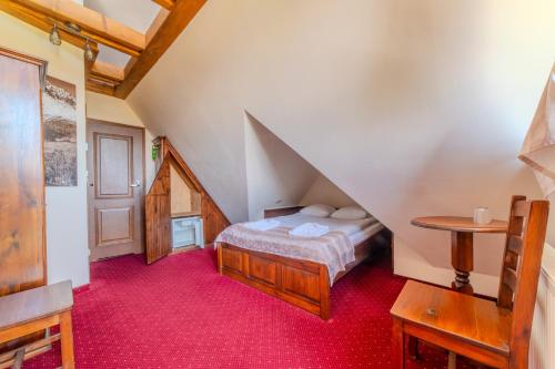 a attic room with a bed and a table at Pensjonat Sekuła*** in Bukowina Tatrzańska