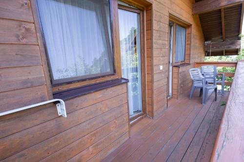 a front porch of a wooden house with a table and chairs at Fantasia Hotel in Polyana