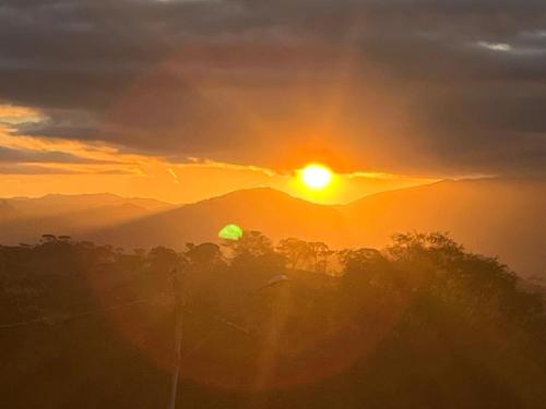 a sunset in the mountains with trees in the foreground at Chalé Estância da Pinha seu Refúgio na Montanha in Santo Antônio do Pinhal