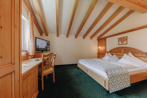 a bedroom with a bed and a desk and a computer at Hotel Hirschen in Silbertal