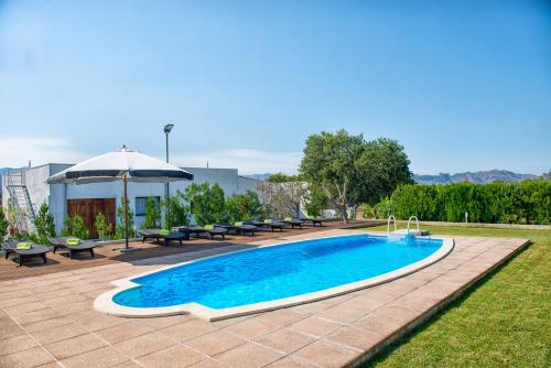 una piscina con bancos y sombrilla en Sa Figuera Roja, en Alcudia