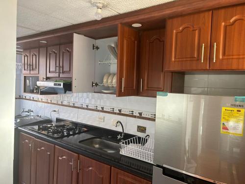 a kitchen with wooden cabinets and a sink and a refrigerator at La casita in Bogotá