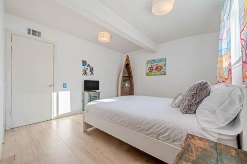 a white bedroom with a bed and a tv at Middlebury Heights with Pool in Los Angeles