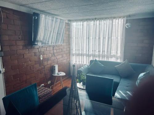 a living room with a blue couch and a brick wall at La casita in Bogotá