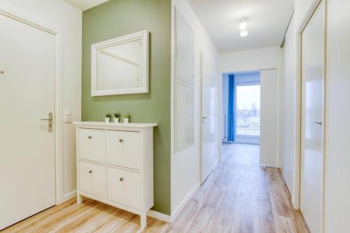 un couloir avec une commode blanche et des murs verts dans l'établissement Kabala - ParisNord Villepinte CDG StadedeFrance, à Bondy