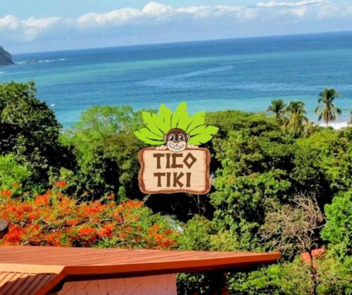 a sign for a tikiiki restaurant with the ocean in the background at Tico Tiki Vacation Villa, 3 Bedroom in Sámara