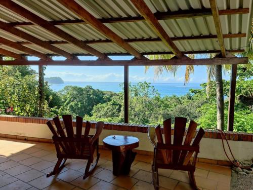 two chairs and a table on a porch with a view at Tico Tiki Vacation Villa, 3 Bedroom in Sámara