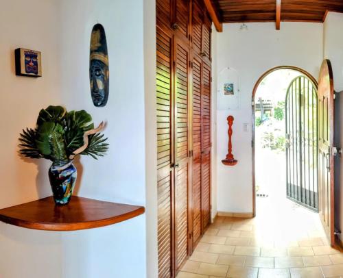 a hallway with a vase on a wooden shelf next to a door at Tico Tiki Vacation Villa, 3 Bedroom in Sámara