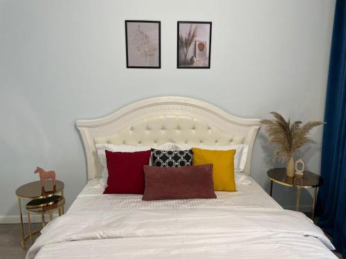 a bedroom with a white bed with colorful pillows at Nexpo City уютные апартаменты возле ЭКСПО in Prigorodnyy
