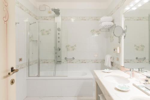 a bathroom with a shower, sink, and mirror at Duchessa Isabella Hotel & SPA in Ferrara