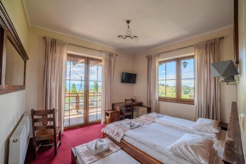 a bedroom with two beds and a desk and windows at Pensjonat Sekuła*** in Bukowina Tatrzańska