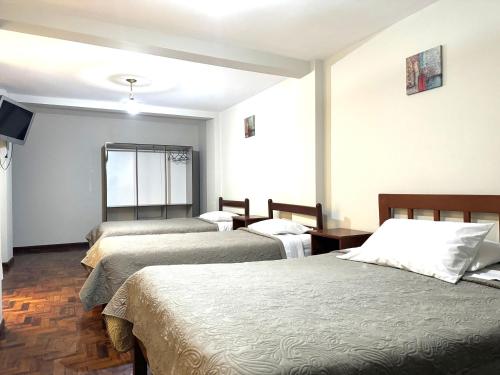 a hotel room with three beds and a window at Hotel Los Angeles in Arequipa
