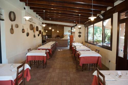 a row of tables in a restaurant with red and white linens at Alle Roncole in Busseto