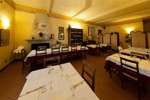 a restaurant with white tables and chairs and a fireplace at Alle Roncole in Busseto