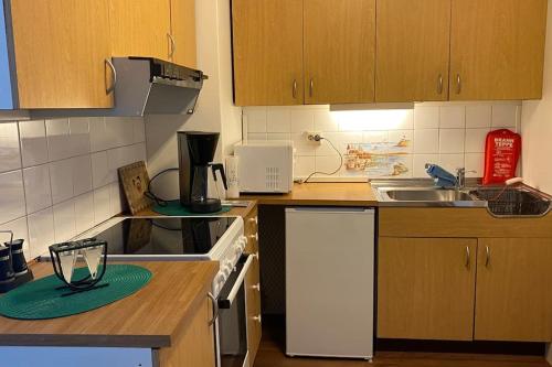 a kitchen with wooden cabinets and a stove top oven at Cozy apartment near city center and nature in Kristiansund