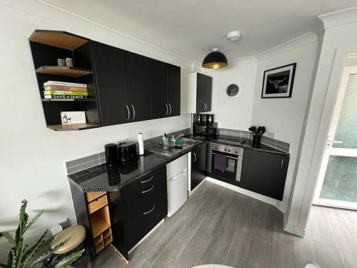 a kitchen with black cabinets and a wooden floor at Elro House Holiday Let in Tillicoultry