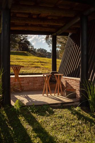 two picnic tables on a porch with a view of a field at Pousada Morada das Araucarias in Pôrto Vitória