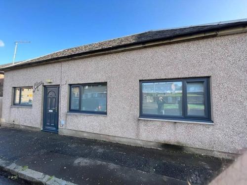 a building with windows and a person standing outside at Elro House Holiday Let in Tillicoultry