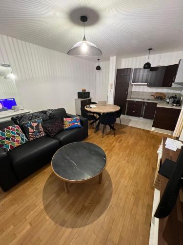 un salon avec un canapé noir et une table dans l'établissement Appartement Longjumeau, à Longjumeau