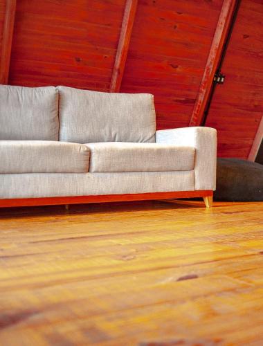 a couch sitting in a room with a wooden floor at Pousada Morada das Araucarias in Pôrto Vitória