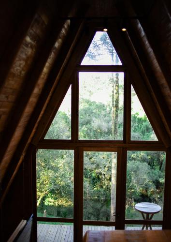 a window in a cabin looking out at the forest at Pousada Morada das Araucarias in Pôrto Vitória