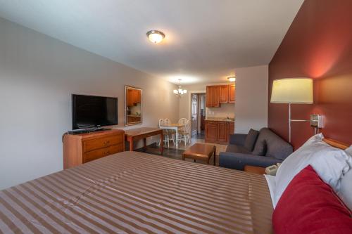 a bedroom with a bed and a living room at Sahara Courtyard Inn Penticton in Penticton