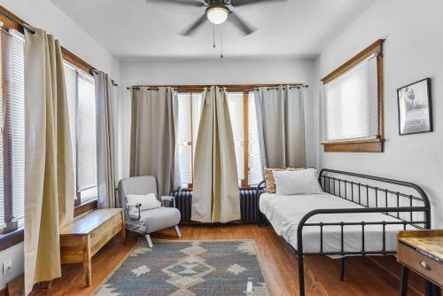 a bedroom with a bed and a chair and windows at Luxury Midtown Home with Historic Charm in Omaha
