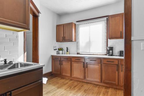a kitchen with wooden cabinets and a sink and a window at Luxury Midtown Home with Historic Charm in Omaha