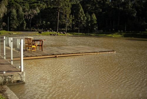 a table and chairs on a dock in a body of water at Pousada Morada das Araucarias in Pôrto Vitória