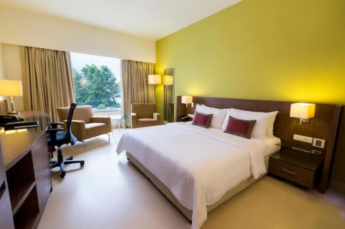 バンガロールにあるラダ リージェント エレクトロニック シティの大きなベッドとデスクが備わるホテルルームです。