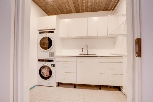 ロヴァニエミにあるVilla Redwoodのキッチン(白いキャビネット、洗濯機、乾燥機付)
