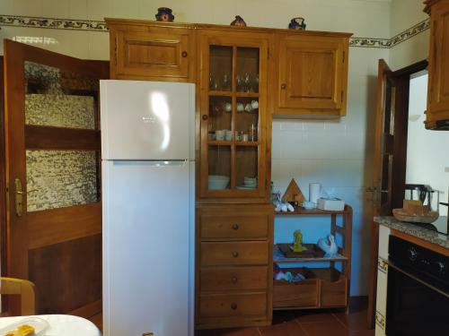 a kitchen with a white refrigerator and wooden cabinets at Cruzeiro - Guest House in Vale de Porco