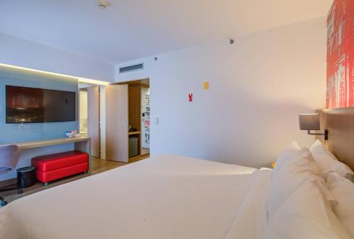 a bedroom with a large white bed and a red chair at Radisson RED Campinas in Campinas