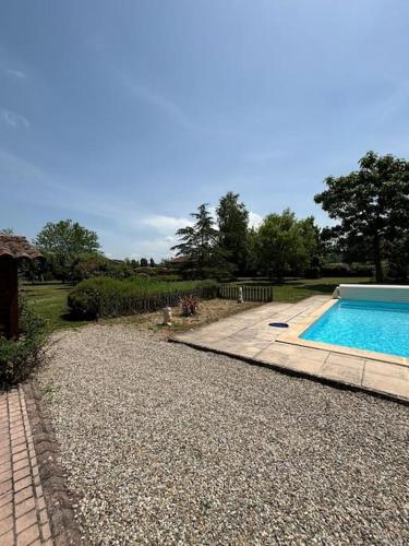 une cour avec une piscine et une allée en gravier dans l'établissement La Vie en Rose, à Léran