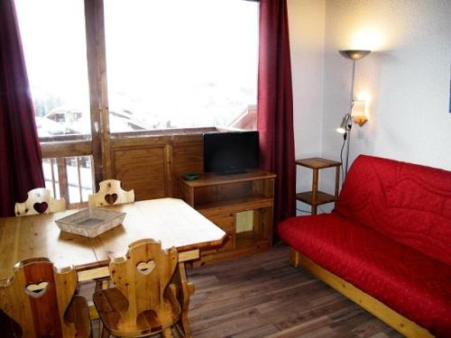 Cette chambre comprend un lit, une table et un canapé rouge. dans l'établissement Résidence Les Hameaux I - HAMEAUX 1 438 MAE-5151, à La Plagne Tarentaise