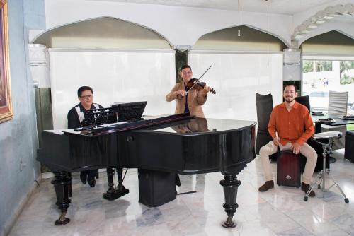a group of three men sitting around a piano at Villa Bejar Cuernavaca in Cuernavaca