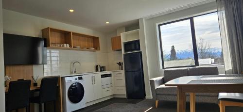 a kitchen with a washer and a table and a window at Alps Motel & Apartments in Twizel