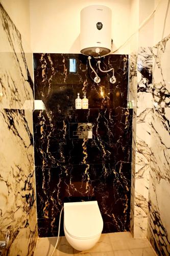 a bathroom with a toilet and a black marble wall at Stay Inn Kaashvi (A unit of Admire India Tourism Pvt. Ltd.) in Varanasi