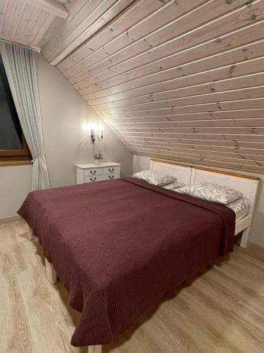 a bedroom with a large bed with a wooden ceiling at Homestead of Happiness in Zalioji