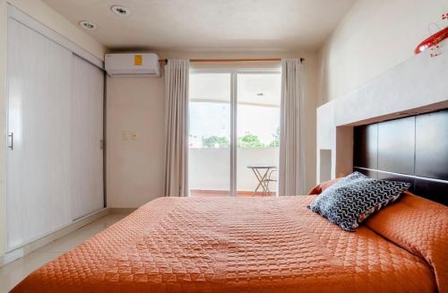 een slaapkamer met een bed met een oranje sprei en een raam bij Departamento en centro Cancún in Cancun