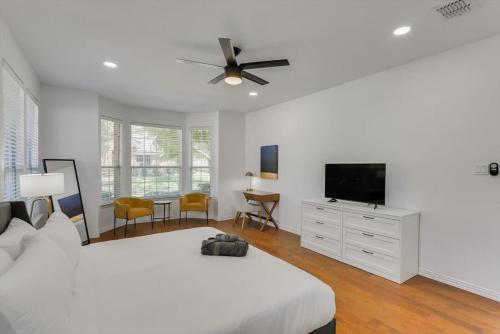 a white bedroom with a bed and a flat screen tv at Luxury Mansion Paradise - Cinema Room, Pool, Spa in Rowlett