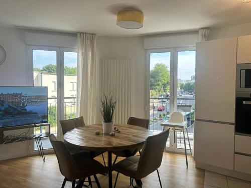 un salon avec une table, des chaises et une télévision dans l'établissement Le Timbaud, T4 cosy, balcon, parking, aux portes de Paris, à Drancy