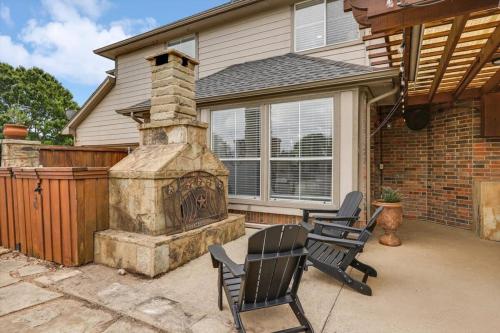 a patio with two chairs and a stone fireplace at Stunning 6BR Pool - Great for Big Groups in Rowlett