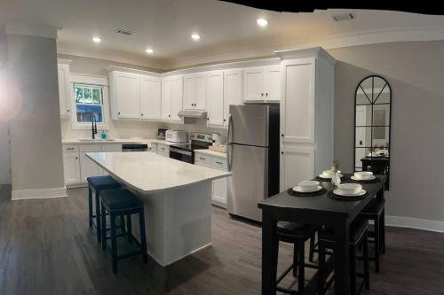 a kitchen with white cabinets and a table and a refrigerator at Charming Gainesville Townhome 3 in Gainesville