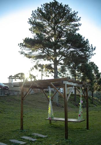 a wooden swing in a field with a tree at Pousada Morada das Araucarias in Pôrto Vitória