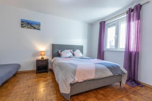 - une chambre avec un lit et une fenêtre avec des rideaux violets dans l'établissement Charmant T2 au pied des Pyrénées - Argeles Gazost, à Argelès-Gazost