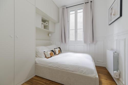 Cette chambre blanche dispose d'un lit avec deux oreillers. dans l'établissement New Snug flat in the Heart of Le Marais, à Paris